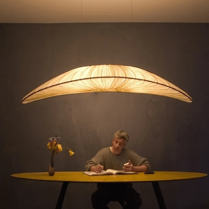 Hand-knit straw-look pendant light with golden fibers – shown lit in a room setting