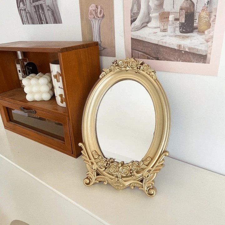 Oval wood-look mirror framed by gold molding – shown in a room setting (2)