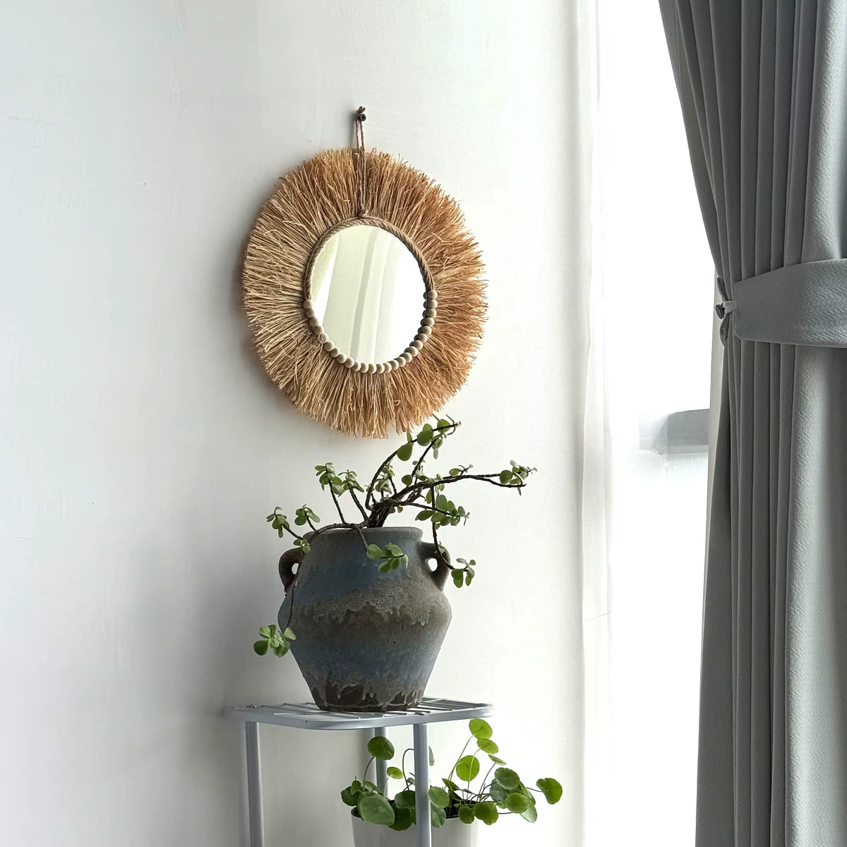 Boho round straw mirror with warm golden highlights – shown in a room setting