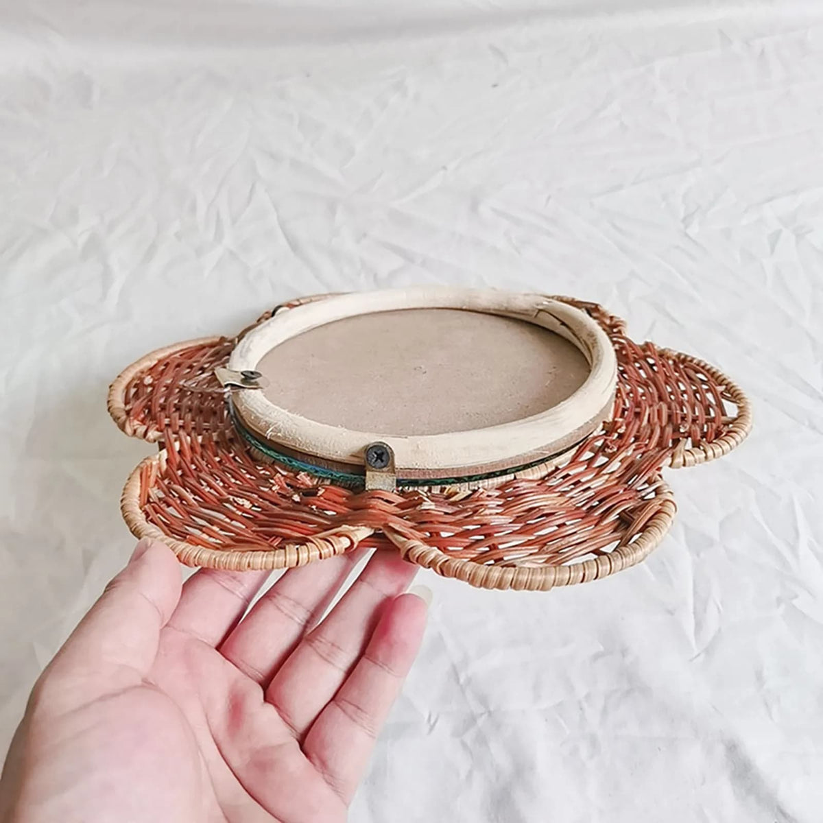 Natural rattan flower wall mirror with braided petals and a circular center – shown in use