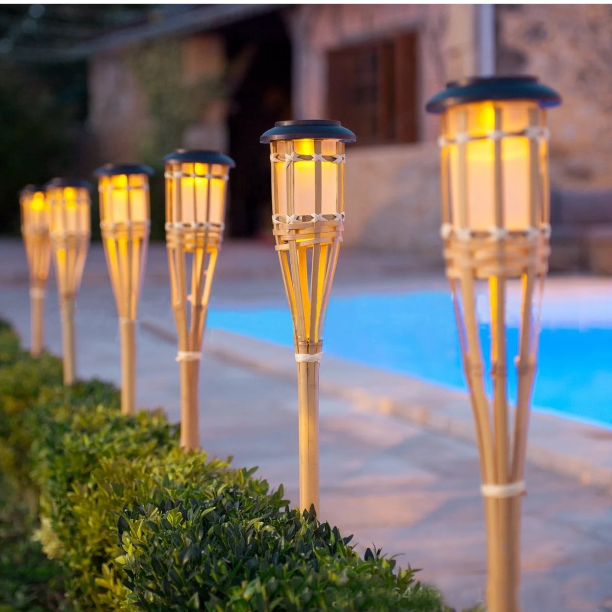 Set of 12 natural color rattan solar lanterns – shown lit outdoors