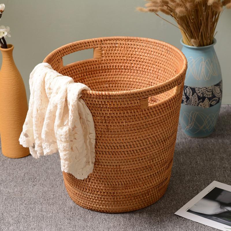 Structured natural rattan laundry hamper with two side handles – shown in a room setting