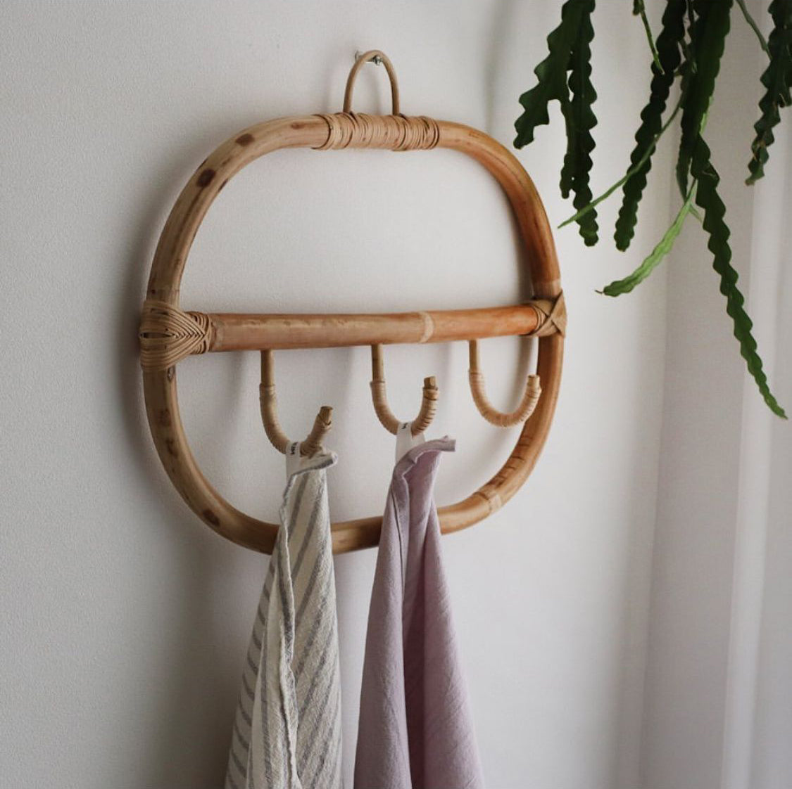 Rectangular natural rattan coat rack with three braided hooks – shown in a room setting