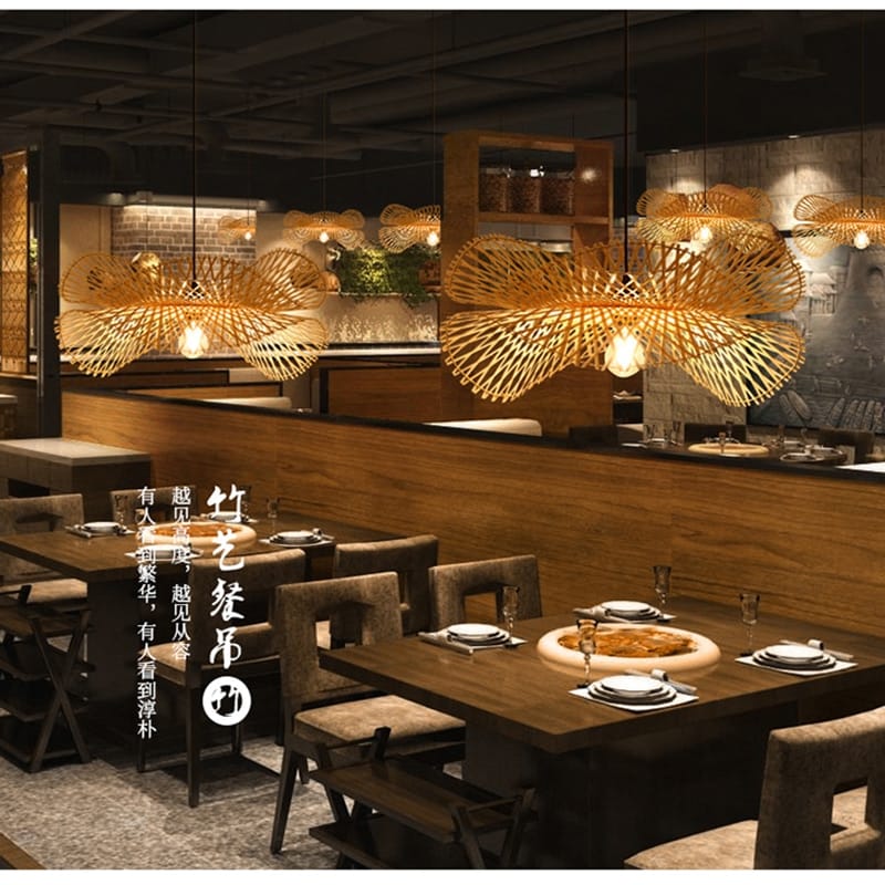 Handwoven spiral bamboo and rattan ceiling light – shown lit in a room setting
