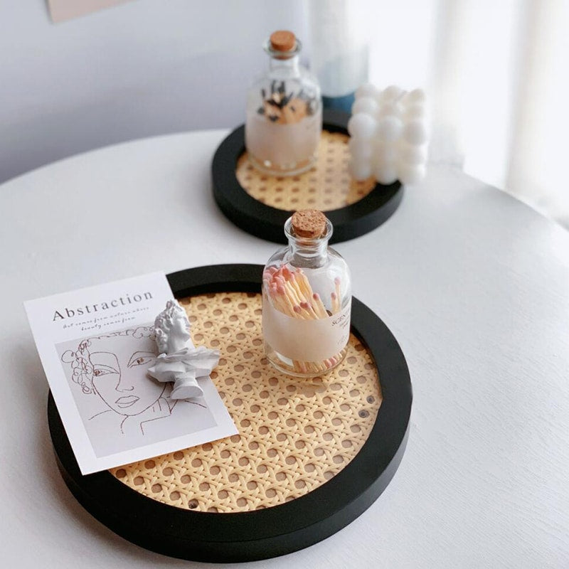 Round decorative rattan tray with a slightly raised rim – black variant, shown in a room setting