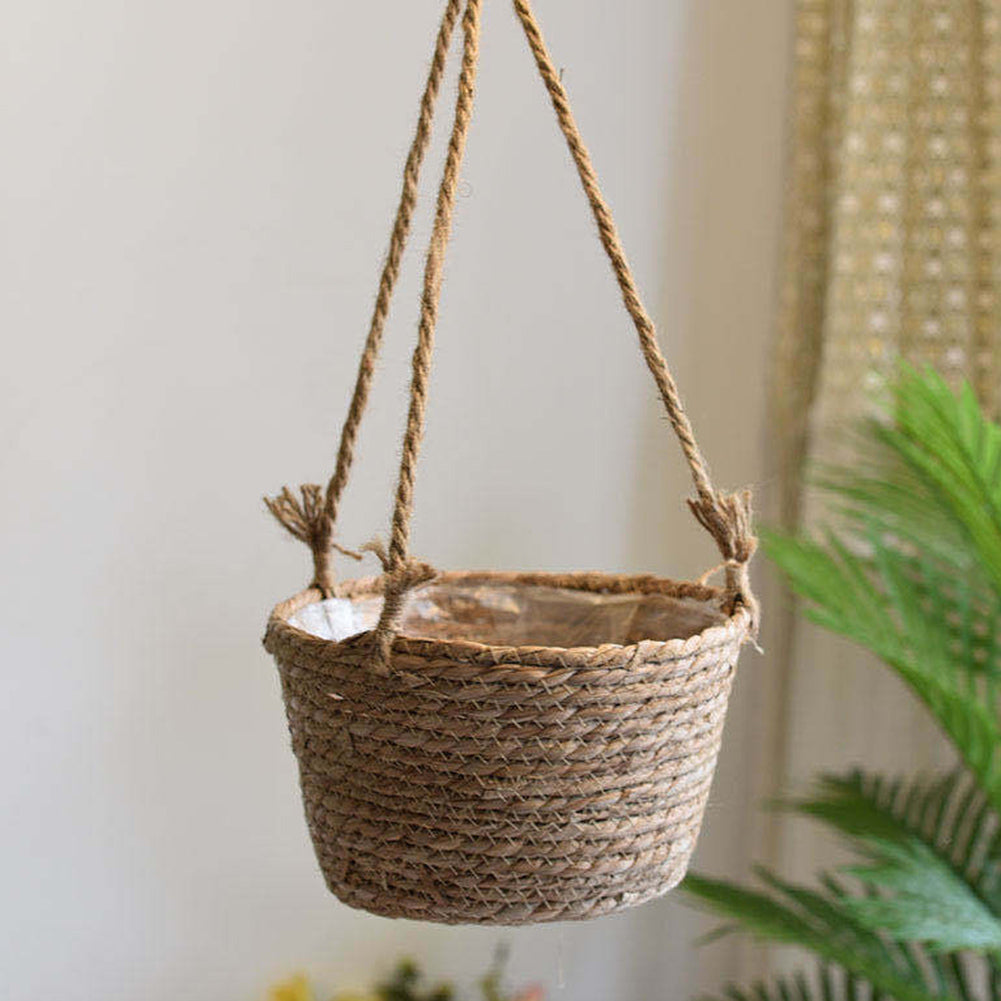 Hanging natural rattan plant holder with a round frame and fringes – shown in a room setting