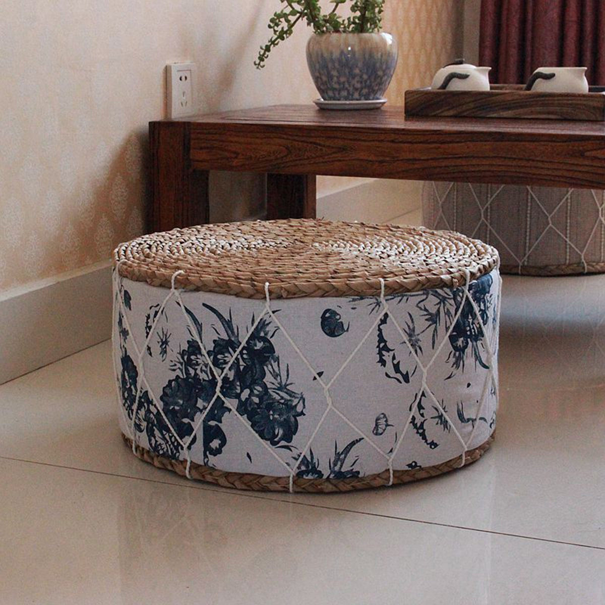 Round pouf with green botanical motifs woven on a white ground – shown in a room setting