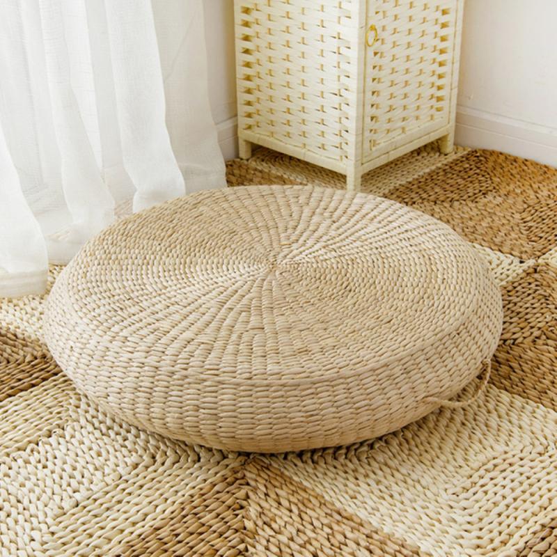 Light rattan pouf with a built-in handle – shown in a room setting