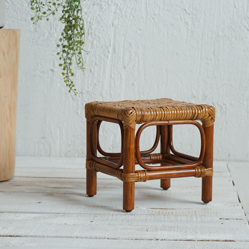 Dark brown wood footstool with a hand-braided rattan seat – shown in a room setting