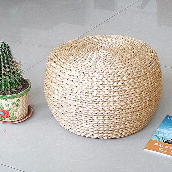 Round rattan footstool with a cushioned seat – shown in a room setting