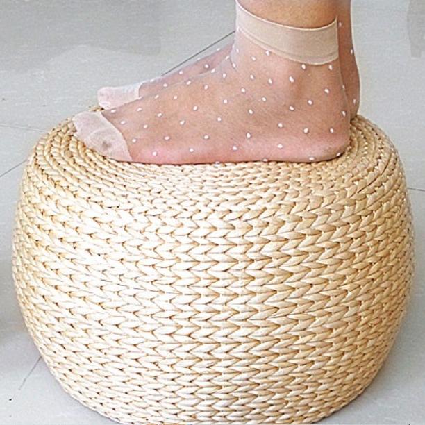 Round rattan footstool with a cushioned seat – shown in use