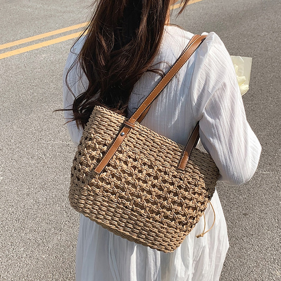 Beige straw beach bag with zip pockets – worn by a model