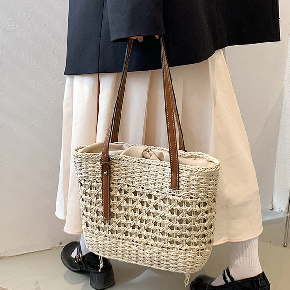 Beige golden straw beach handbag – worn by a model
