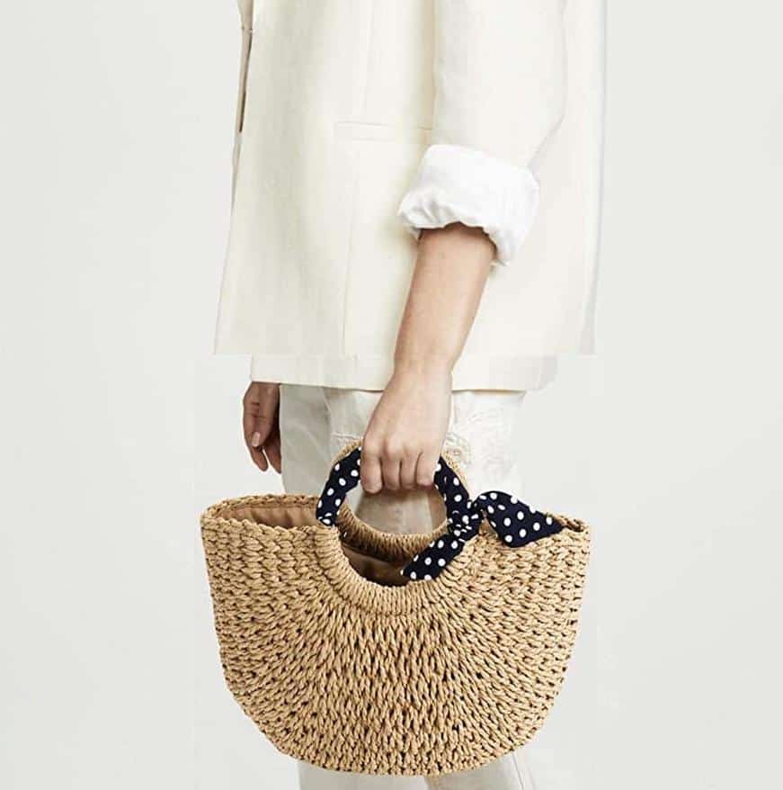 Rattan beach bag with a navy polka-dot scarf handle – worn by a model