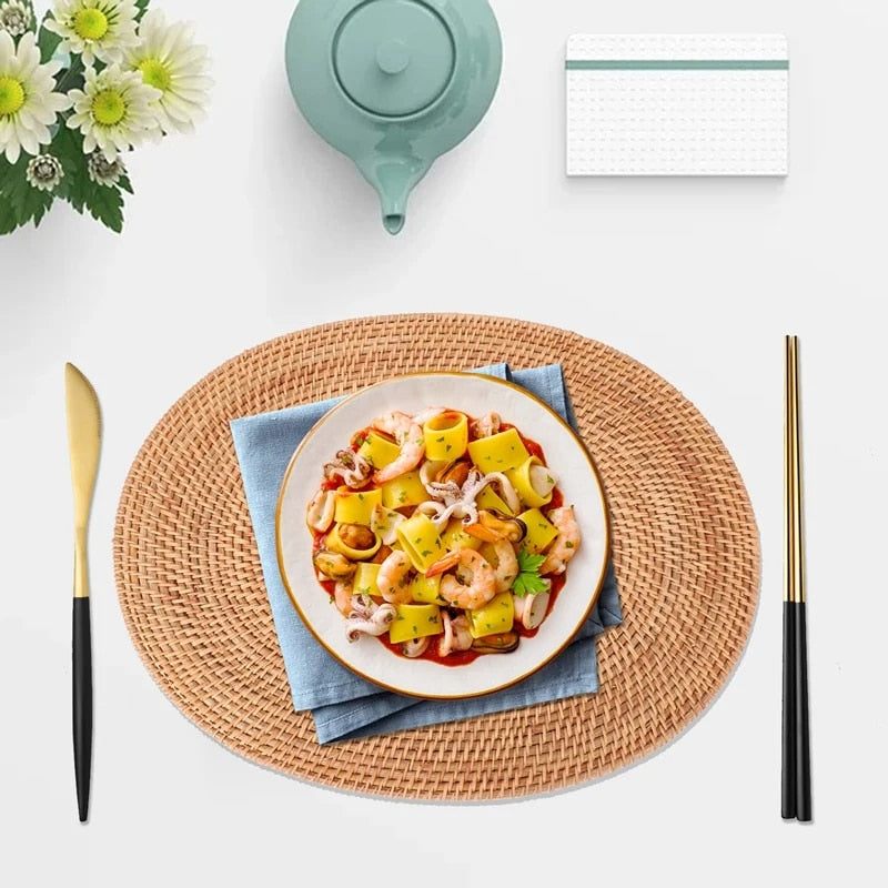 Oval natural rattan placemat in an untreated honey tone – shown in a room setting