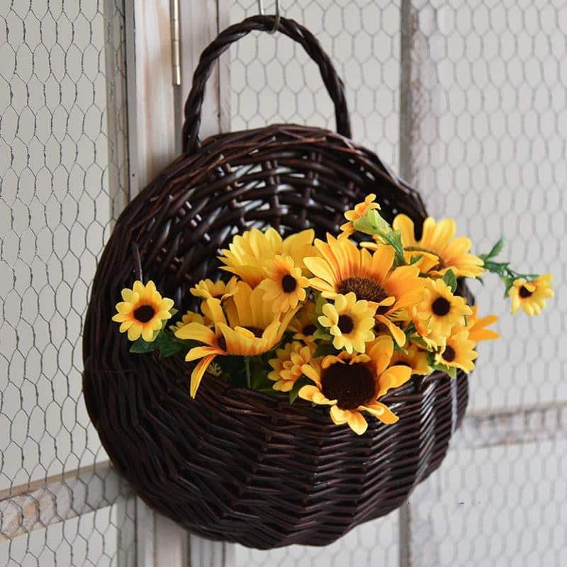 Round hanging rattan wall vase with golden highlights – brown version, shown in a room setting